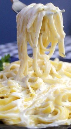 a fork full of noodles being lifted from the plate