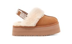 The Funkette evolves our iconic Coquette Slipper, updating its design with layered platform soles for a funky, retro-style statement. Keeping the same slip-on silhouette and soft sheepskin lining as the original, we add a graphic UGG logo backstrap to help secure your foot. Pair with dark denim and a striped top. | Suede upper. Sheepskin collar. Elastic strap with UGG graphic. 10mm sheepskin lining. 10mm sheepskin Insole. EVA outsole. Polyester binding. 2" heel height. Woven label with UGG logo Ugg Funkette, Ug Boots, Ugg Store, Wool Shoes, Short Leather Boots, Suede Slippers, Ugg Slippers, Nike Shox, Platform Slippers