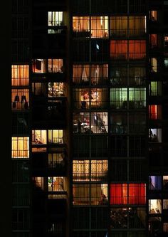 many windows are lit up at night in an office building's dark facades