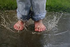 a person standing in the water with their bare feet sticking out from underneath them and splashing around