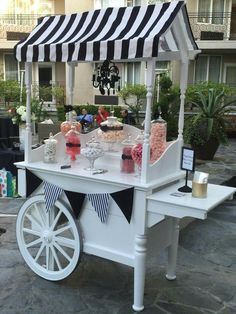 a white cart with black and white striped awning on it's side filled with candy