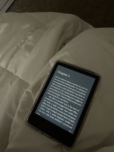 a kindle sitting on top of a white bed