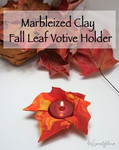 a candle that is sitting next to some leaves on a table with the words marbleized clay fall leaf votive holder