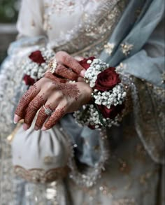 a woman in a wedding dress holding her hands with hennap and flowers on it