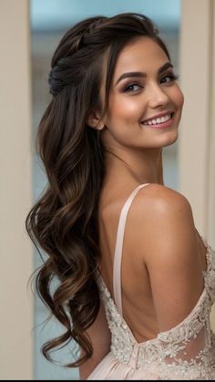 a woman with long hair wearing a wedding dress and smiling at the camera while standing in front of a doorway