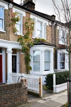 a row of brick houses with white picket fence and red door in the foreground