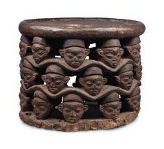 an old wooden stool with carved faces on it