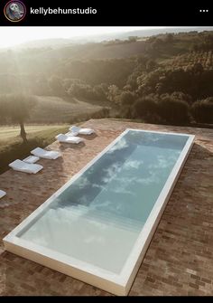 an empty swimming pool in the middle of a brick patio with lounge chairs around it