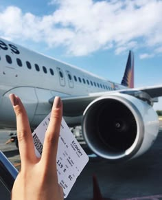 a person holding up their hand with a ticket in front of an airplane