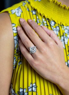 a woman's hand with a diamond ring on her left wrist, wearing a yellow dress