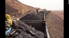 there are many people standing on the side of a hill with rocks and gravel in front of them