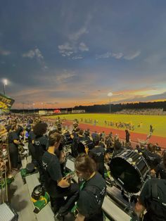 a group of people sitting on top of a field next to each other near a band