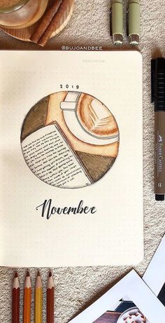 an open notebook with the words november written in it next to some crayons and pencils