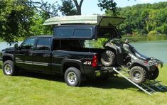 a truck with a camper attached to the back parked in front of a lake