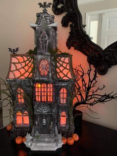 a lighted halloween house sits on a table in front of a mirror