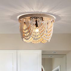 a white chandelier hanging from the ceiling in a room with wooden floors and cabinets