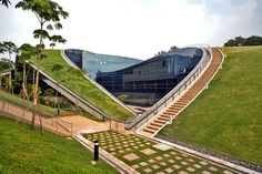 an unusual building with grass on the roof and stairs leading up to it's entrance