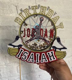 a hand holding a happy birthday clock with the word jordan on it and two birds