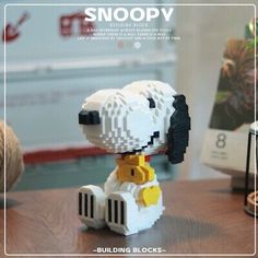 a lego snoopy dog sitting on top of a wooden table next to a ball of yarn