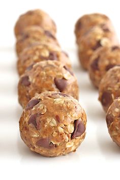 chocolate chip cookies and oatmeal balls are lined up on a white surface