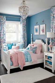 a bedroom with blue walls, pink and white bedspreads, and floral curtains