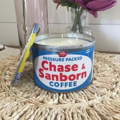 a glass jar with a candle and some flowers in it on a woven table cloth