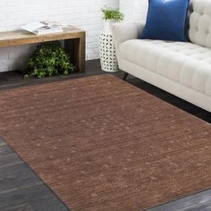 a living room with a white couch and brown rug on top of wooden flooring