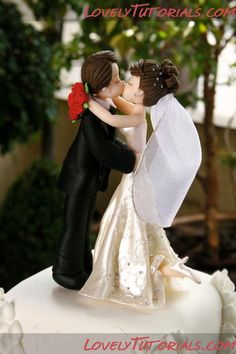 a bride and groom kissing on top of a cake