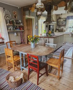 a kitchen with wooden floors and an old fashioned dining room table surrounded by vintage chairs