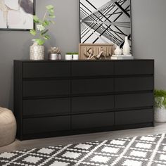 a black dresser sitting in a living room next to a chair and pictures on the wall