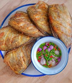 a plate topped with fish next to a bowl of vegetables