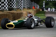 a green race car driving down a road with hay bales in the back ground