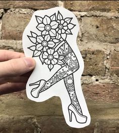 a person holding up a sticker with flowers on it in front of a brick wall