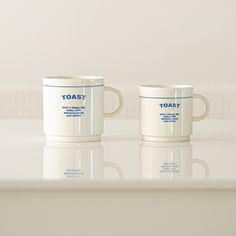 two white coffee mugs sitting on top of a counter