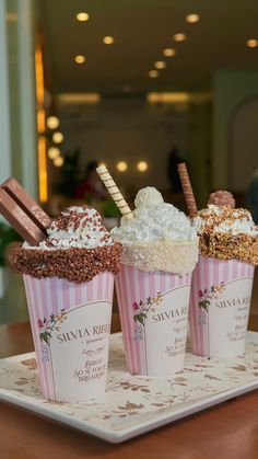 three ice cream sundaes on a tray with chocolate and marshmallow toppings