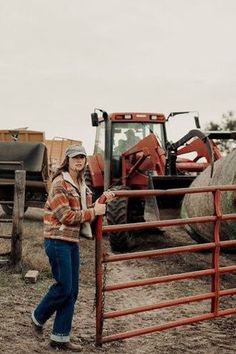 a woman standing next to a tractor behind a fence