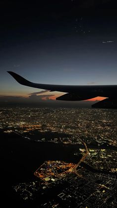 an airplane wing flying over a city at night