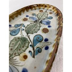 a decorative ceramic dish with blue and green designs on the bottom, sitting on a white surface