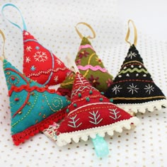 four christmas tree ornaments are sitting on a polka dot tablecloth background, one is red and the other is green