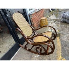 a wooden rocking chair sitting on top of a sidewalk next to a brick wall and door