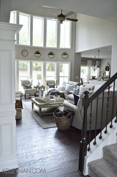 a living room filled with lots of furniture next to a stair case in front of a window