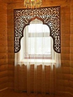 an ornate window with sheer curtains and a chandelier