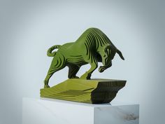 a green sculpture on top of a white pedestal in the shape of a bull with its mouth open