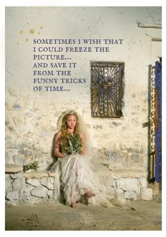 a woman in a wedding dress sitting on a stone wall next to a blue door