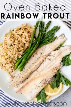 baked rainbow trout with rice and asparagus on a white plate next to lemon wedges