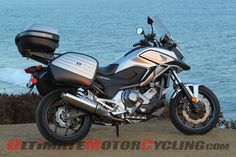 a silver motorcycle parked on top of a hill next to the ocean