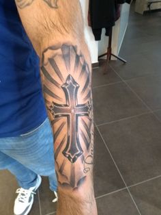 a man with a cross tattoo on his arm is standing in front of a tile floor