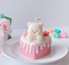 there is a cake shaped like a bear on the plate with flowers and candies around it