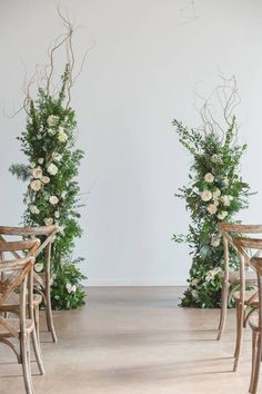 two wooden chairs sitting next to each other with flowers on the back and one chair in front