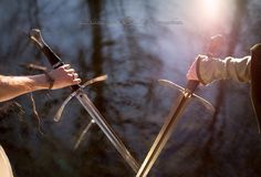 two people holding swords in their hands with the sun shining on them and trees behind them